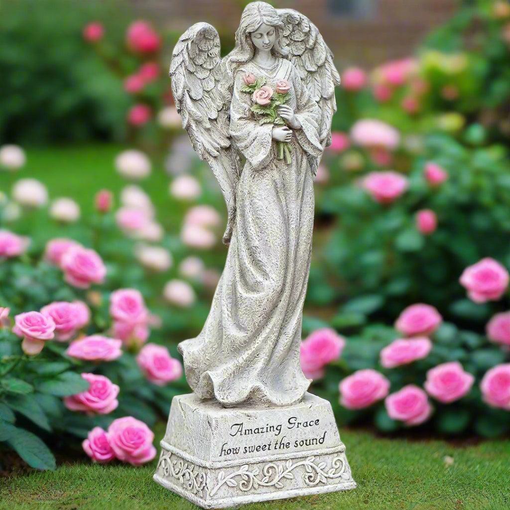 Ángel conmemorativo con flores en el jardín | Amazing Grace