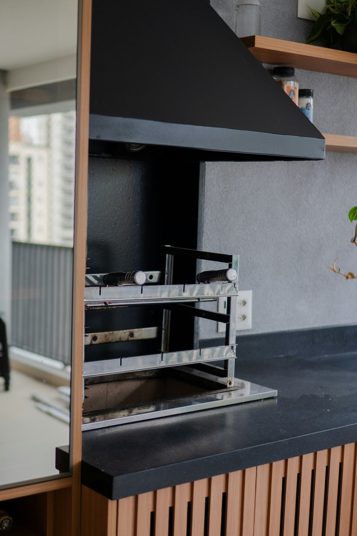 Barbecue grill with black hood on a wooden cabinet base