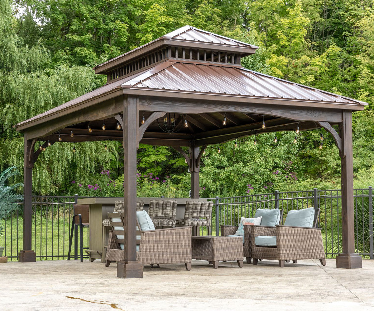 Wooden gazebo with outdoor furniture on a deck surrounded by trees