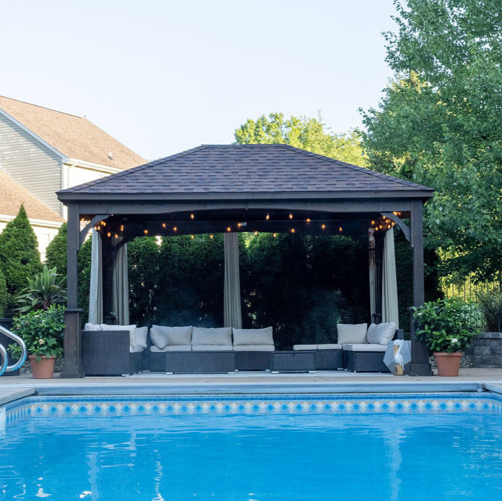 Gazebo with outdoor furniture by a pool in a backyard setting