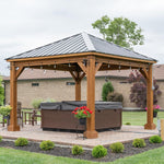 Wooden gazebo with a hot tub underneath, surrounded by a garden setting.